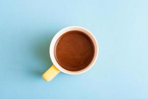 una taza de café caliente en colores pastel. café turco en una taza amarilla sobre fondo azul. foto