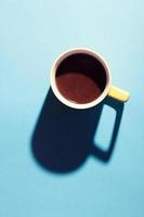 A cup of hot coffee in pastel colors. Turkish coffee in a yellow mug on blue background. photo