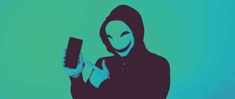 hacker anónimo y mascarilla con smartphone en la mano. foto