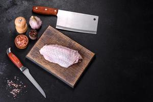 Fresh raw turkey wing with spices and herbs on a wooden cutting board photo