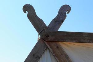 antigua tienda vikinga hecha de madera y tela frente a un cielo azul foto