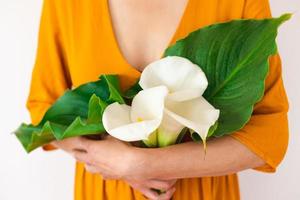 A woman holds a bouquet of callas in her hands photo