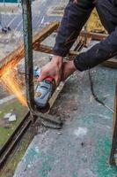 un trabajador corta metal con un molinillo. foto