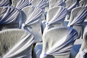 View from behind white wedding seats with gold ribbon decoration photo