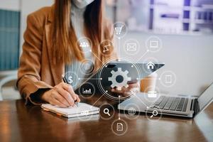 businesswoman or Designer using mobile phone with laptop and digital tablet laptop and document on desk in office with virtual icons network diagram in morning light photo