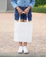 young model holding white tote bag for mockup blank template photo