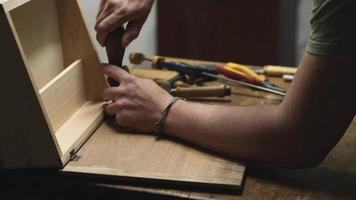 carpintero en el taller hace muebles con una herramienta de mano