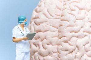 cirujano de personas en miniatura analizando el cerebro del paciente foto