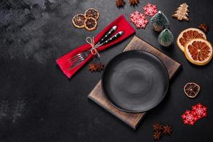 Christmas table setting with empty black ceramic plate, fir tree and black accessories photo