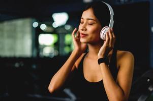 girl in the gym exercising Listening to music with white over-ear headphones and using a digital heartbeat timer. systematic exercise Exercises are structured. photo