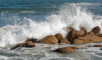 Wave crashes against the rocks of a coast photo