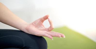 mujer practicando clases de yoga, respirando, meditando sentada en una alfombra de yoga verde, en el hogar. foto