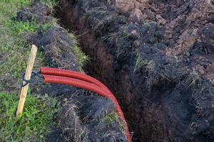 tendido de comunicaciones en el suelo. cable eléctrico rojo. foto