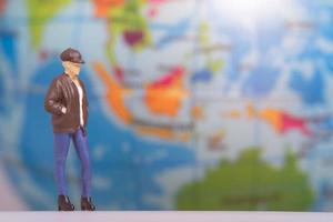 Miniature People Traveler with backpack on The Globe background photo