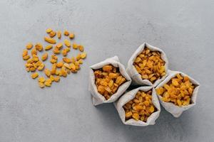 Photo of nutritious organic products in sacks with various beans. Vegan food concept. Buckwheat, goji, kidney bean, walnuts. Grey background, free space aside