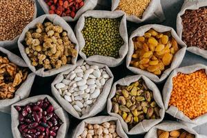 Colourful various beans in cloth sacks. Uncooked assorted legumes. Mulberry, buckwheat, pistache, raisins, almond, garbanzo, others. Healthy cereals. photo