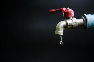 concepto de crisis de escasez de agua dulce debido a cambios ambientales. grifo de agua sin agua corriente sobre un fondo negro hay un espacio de copia. foto