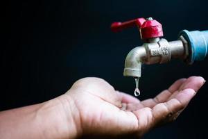 concepto de crisis de escasez de agua dulce debido a cambios ambientales. grifo de agua sin agua corriente sobre un fondo negro hay un espacio de copia. foto