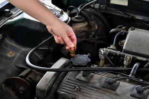 A woman checks the engine oil in an old car parked in the garage before leaving, wiping the car before traveling. photo