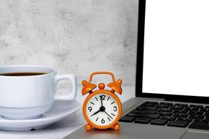 despertador en la computadora portátil con una taza de café en una mesa. el reloj puesto a las 8 en punto. foto