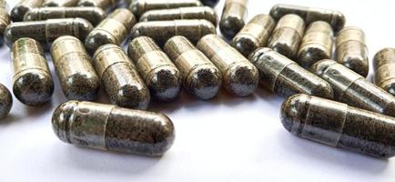 Herbal medicine black cumin capsules with negative space isolated on the gray white studio background. Nigella sativa. Suitable for promotion of health industry and company. photo