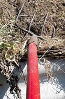 Fork with red handle for composting, recycling lawn and garden waste. Forks stuck in compost. Making and mixing compost in the backyard. Organic fertilizer for garden plants. photo