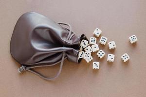 Set of gaming dice rolled out of leather bag on brown background. Concept with copy space for games, game board, role playing game, dnd, risk, chance, good luck or gambling. Toned image top view. photo