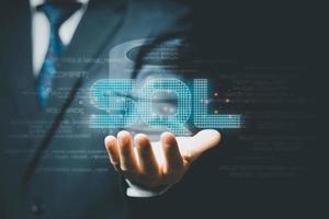 Businessman hand showing SQL word and SQL or Structured Query Language code on background. photo
