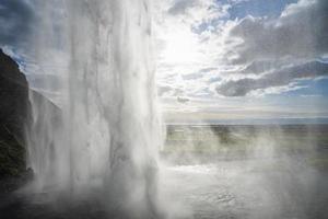 Close-up of Seljalandsfoss with beautiful mist flowing from mountain against sky photo