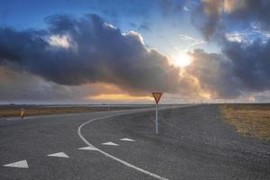 sol brillando a través de las nubes sobre una carretera vacía contra el cielo durante la puesta de sol foto