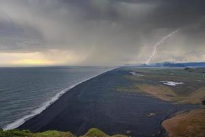 Lightning weather over black sand beach against cloudy sky during sunset photo