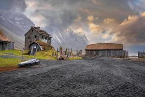 casas de madera en el histórico pueblo vikingo bajo la montaña vestrahorn al atardecer
