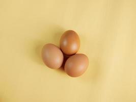 Eggs are laid in groups of three, eggshells with different patterns. Shot in a studio with light and shadows against an eggshell colored background. photo