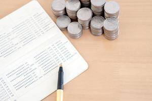 coins and pen on savings account passbook photo