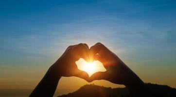 Child hands in heart shape against sky sunset background. Love concept. photo