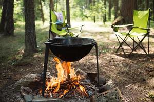 cocinar en un campamento en un fuego abierto en un caldero. picnic al aire libre, vacaciones de verano, accesorios de viaje foto