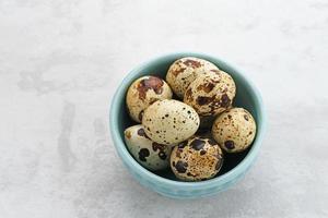 Fresh Quail Eggs served in bowl on grey background. Space for text photo