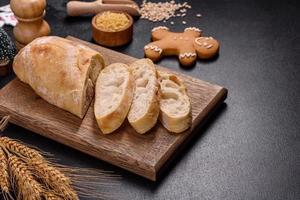 French baguette bread sliced on a wooden cutting board against a dark concrete background photo