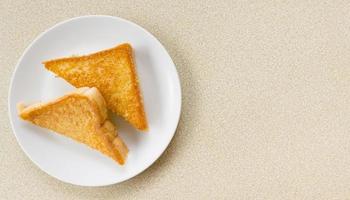 rebanadas triangulares de dos piezas de pan tostado hechas con harina de trigo blanco y una rebanada de queso cheddar en un plato blanco. foto