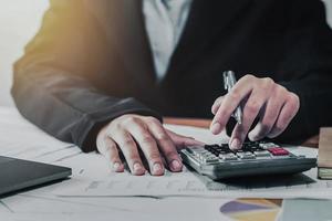 business accounting finance concept. accountant using calculator for calculate  with laptop working in office photo