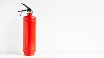 Red fire extinguisher on a white wall background photo