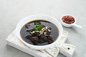 Rawon, Indonesian Traditional beef black soup. Served on a bowl with mung bean sprouts, chilli paste and salted egg photo