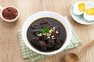 Rawon, Indonesian Traditional beef black soup. Served on a bowl with mung bean sprouts, chilli paste and salted egg photo