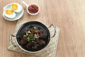 Rawon, Indonesian Traditional beef black soup. Served on a bowl with mung bean sprouts, chilli paste and salted egg photo