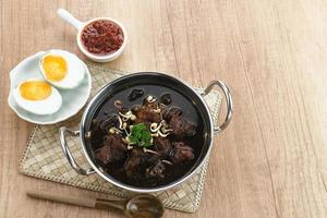 Rawon, Indonesian Traditional beef black soup. Served on a bowl with mung bean sprouts, chilli paste and salted egg photo