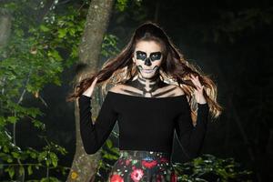 Halloween Vampire Woman portrait over scary night background. Vampire makeup Fashion Art design. Model girl in Halloween costume and make up. photo