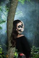 Halloween Vampire Woman portrait over scary night background. Vampire makeup Fashion Art design. Model girl in Halloween costume and make up. photo