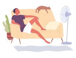 el hombre se sienta en casa en el sofá junto al ventilador y disfruta de la frescura de un día caluroso.