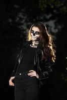 Halloween Vampire Woman portrait over scary night background. Vampire makeup Fashion Art design. Model girl in Halloween costume and make up. photo