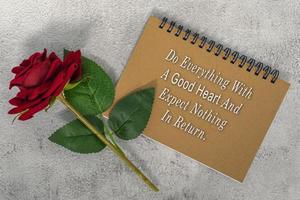 Motivational and inspirational quote on brown note book with red roses. photo